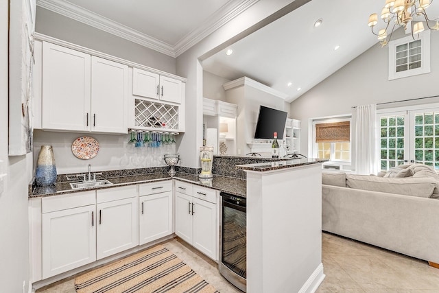 kitchen featuring white cabinets, beverage cooler, dark stone counters, and sink