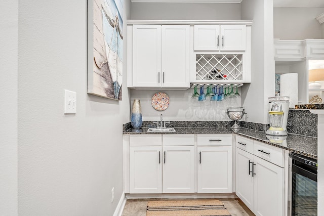 bar featuring wine cooler, white cabinetry, and dark stone countertops