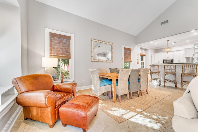 tiled dining room featuring high vaulted ceiling