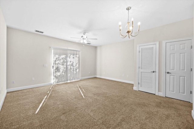 empty room featuring ceiling fan with notable chandelier and carpet floors