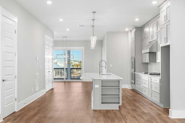 kitchen with sink, tasteful backsplash, a chandelier, decorative light fixtures, and a center island with sink