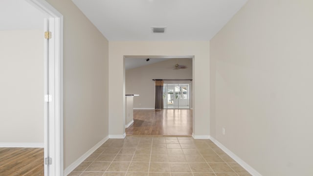 hallway with light tile patterned floors and vaulted ceiling