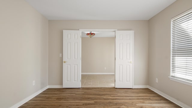 unfurnished bedroom featuring a closet, multiple windows, and hardwood / wood-style flooring