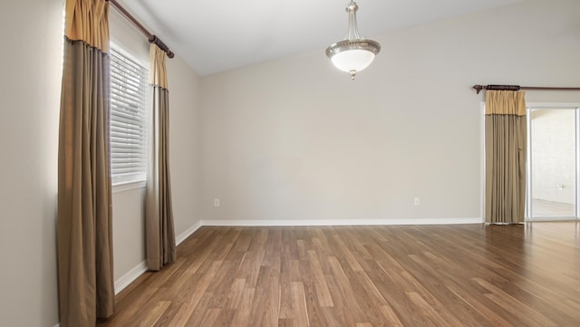 spare room featuring hardwood / wood-style flooring and vaulted ceiling