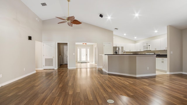 unfurnished living room featuring dark hardwood / wood-style flooring, high vaulted ceiling, and ceiling fan