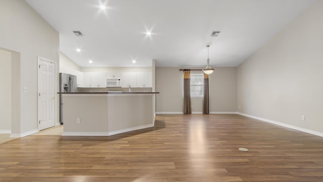 kitchen with stainless steel fridge with ice dispenser, white cabinetry, hanging light fixtures, and light wood-type flooring