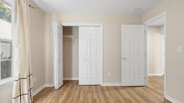 unfurnished bedroom with a closet and light wood-type flooring