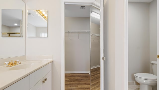 bathroom featuring wood-type flooring, vanity, and toilet