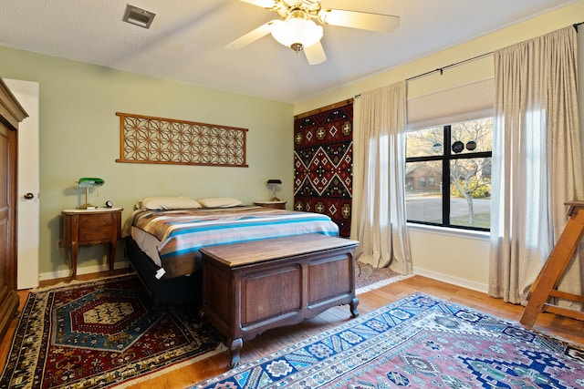 bedroom featuring ceiling fan, light hardwood / wood-style floors, and a textured ceiling