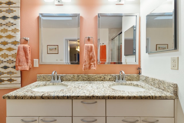 bathroom featuring a shower with door and vanity