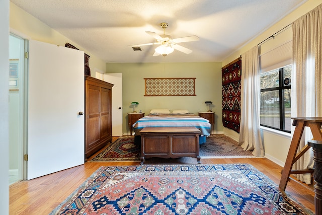 bedroom featuring ceiling fan, light hardwood / wood-style flooring, and a textured ceiling