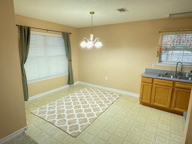 unfurnished dining area featuring a notable chandelier, sink, and a textured ceiling