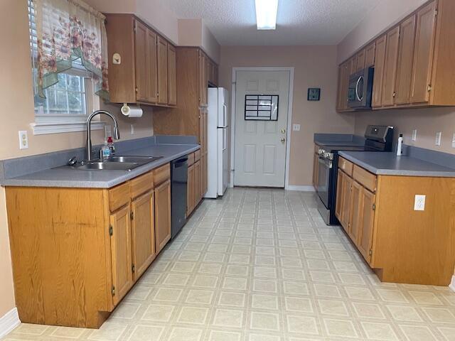 kitchen featuring electric stove, dishwasher, a textured ceiling, white refrigerator, and sink