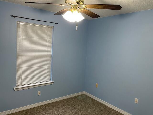 empty room with a textured ceiling, ceiling fan, and carpet floors