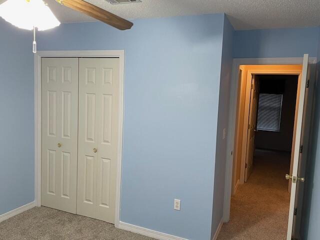 unfurnished bedroom featuring ceiling fan, a closet, carpet, and a textured ceiling