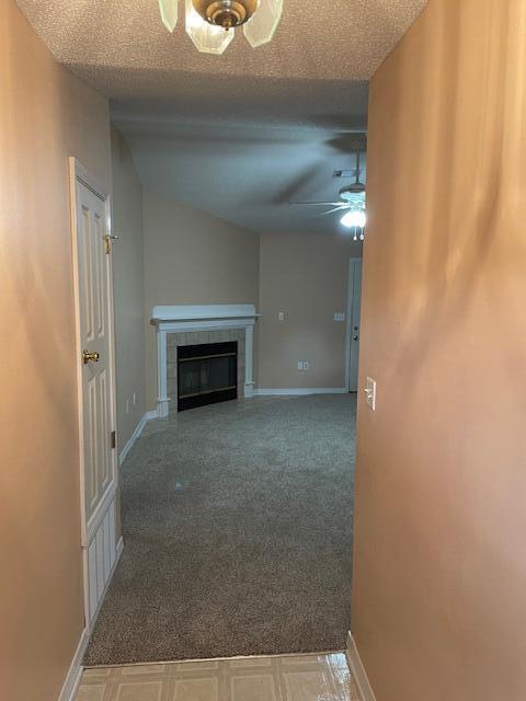 unfurnished living room with ceiling fan, a textured ceiling, and a fireplace