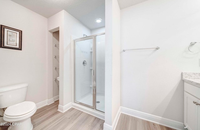 bathroom with hardwood / wood-style flooring, vanity, an enclosed shower, and toilet