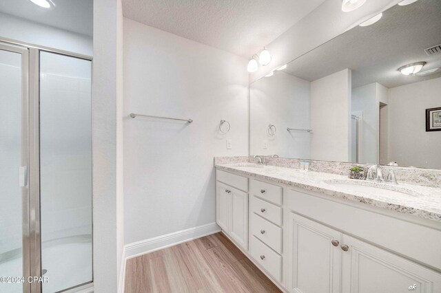 bathroom featuring hardwood / wood-style floors, vanity, a textured ceiling, and walk in shower