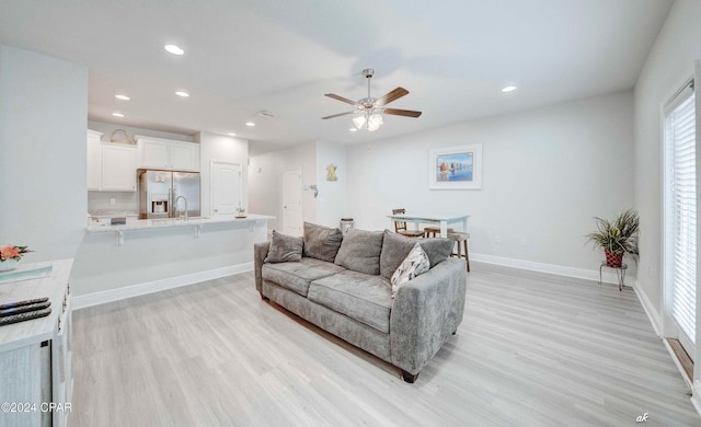 living room with ceiling fan and light hardwood / wood-style flooring