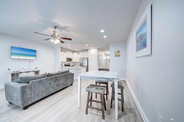 living room with ceiling fan and light wood-type flooring