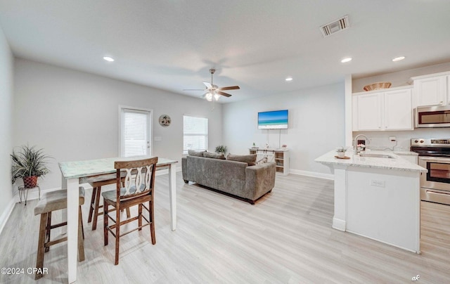 kitchen with light hardwood / wood-style flooring, stainless steel appliances, white cabinetry, and sink