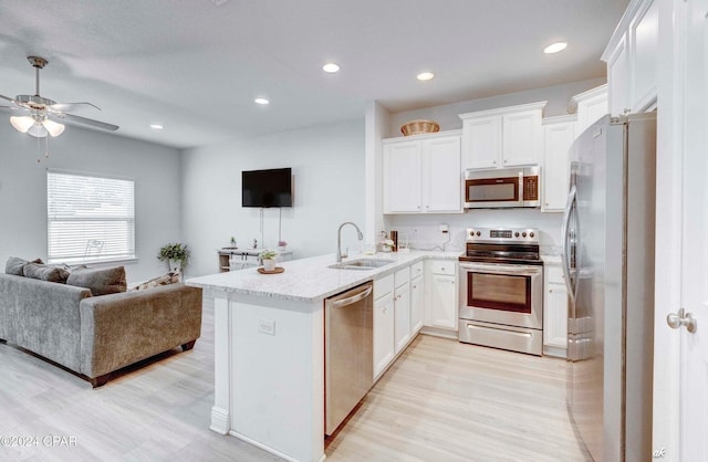 kitchen with sink, kitchen peninsula, light hardwood / wood-style floors, white cabinets, and appliances with stainless steel finishes