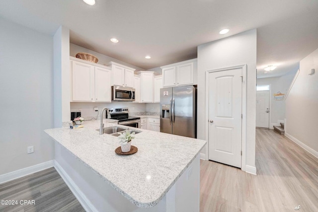 kitchen featuring white cabinets, appliances with stainless steel finishes, kitchen peninsula, and light hardwood / wood-style flooring