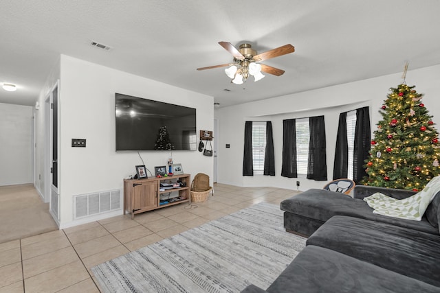 living room with ceiling fan, light tile patterned flooring, and a textured ceiling