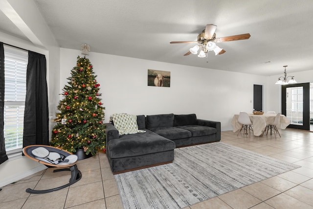 living room with light tile patterned floors, ceiling fan with notable chandelier, and a textured ceiling