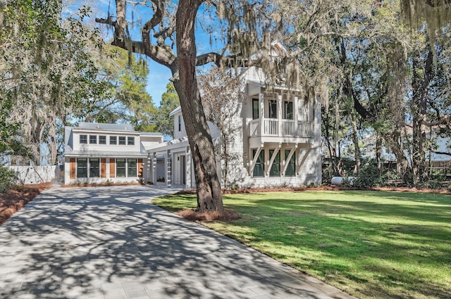 view of front facade with a balcony, a garage, and a front yard