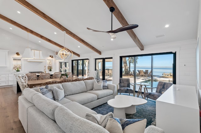 living room featuring vaulted ceiling with beams, hardwood / wood-style flooring, a wealth of natural light, and a water view