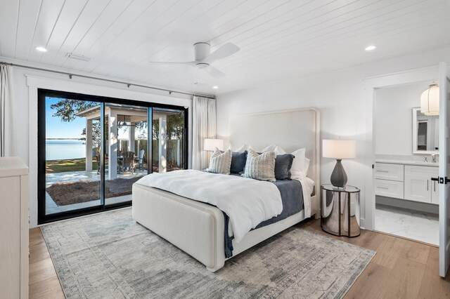 bedroom featuring wood ceiling, access to exterior, a water view, connected bathroom, and light hardwood / wood-style floors