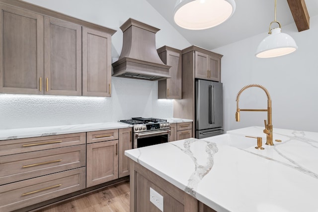 kitchen with appliances with stainless steel finishes, decorative light fixtures, light stone countertops, custom range hood, and light wood-type flooring