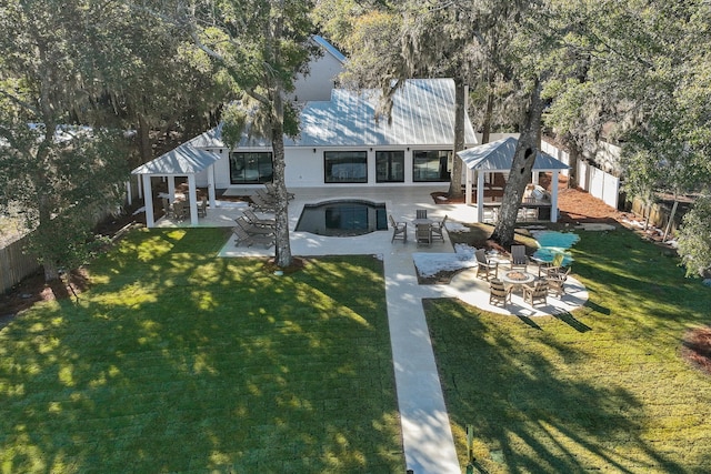 back of property with a gazebo, a fire pit, a lawn, and a patio