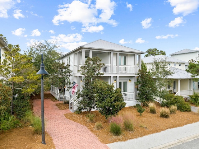 view of front of house with covered porch, french doors, and a balcony