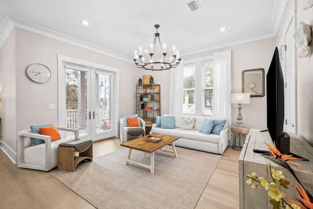 living room with a healthy amount of sunlight, light wood-type flooring, ornamental molding, and an inviting chandelier