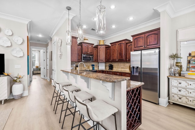 kitchen with kitchen peninsula, appliances with stainless steel finishes, decorative backsplash, a kitchen breakfast bar, and dark stone counters