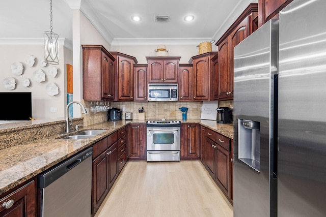 kitchen with decorative backsplash, appliances with stainless steel finishes, ornamental molding, sink, and pendant lighting