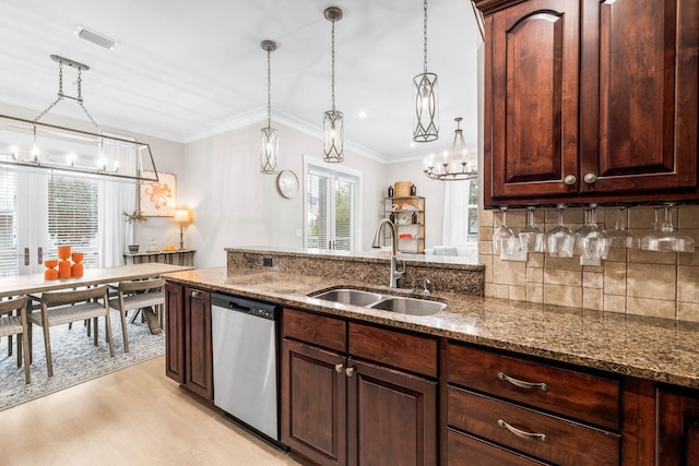 kitchen featuring stainless steel dishwasher, decorative light fixtures, sink, and dark stone counters