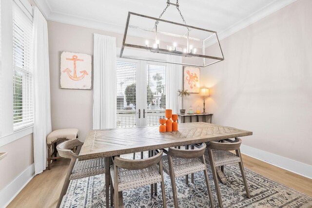 dining area featuring a chandelier, french doors, light hardwood / wood-style flooring, and ornamental molding