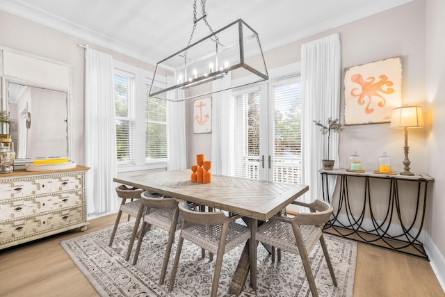 dining space with ornamental molding, french doors, and light hardwood / wood-style flooring