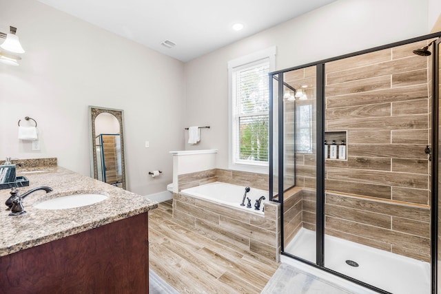 full bathroom featuring hardwood / wood-style floors, vanity, independent shower and bath, and toilet