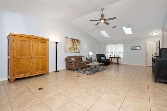 tiled living room with ceiling fan and vaulted ceiling with skylight