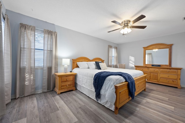 bedroom with ceiling fan, light hardwood / wood-style flooring, and a textured ceiling