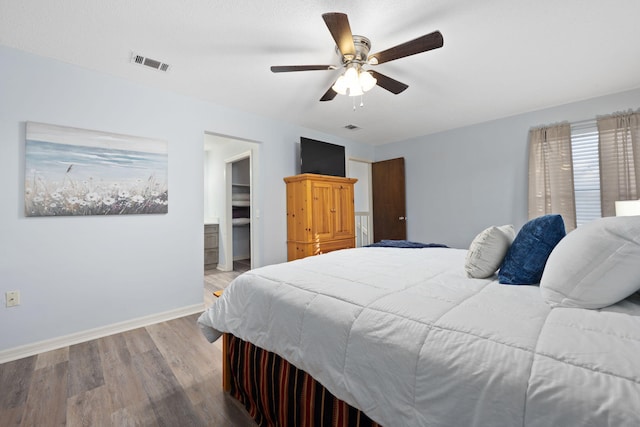 bedroom featuring ceiling fan, a textured ceiling, hardwood / wood-style flooring, and a spacious closet