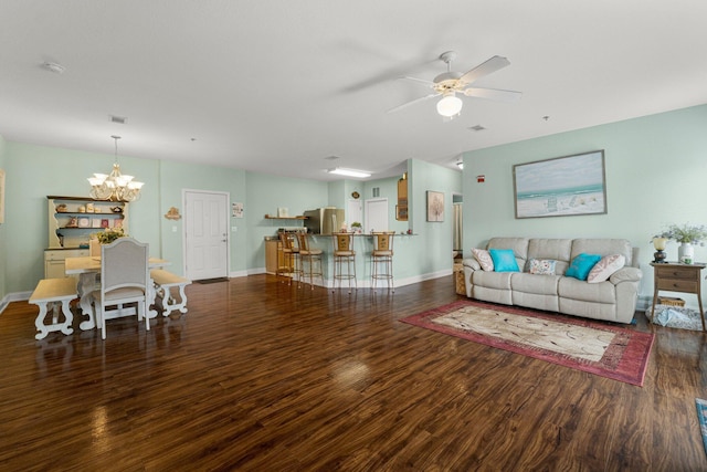 living room featuring dark wood-type flooring and ceiling fan with notable chandelier