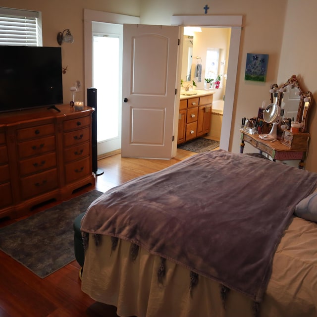 bedroom with connected bathroom, sink, and light hardwood / wood-style floors