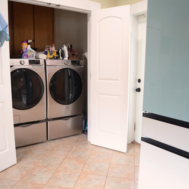 clothes washing area featuring washing machine and clothes dryer and light tile patterned flooring