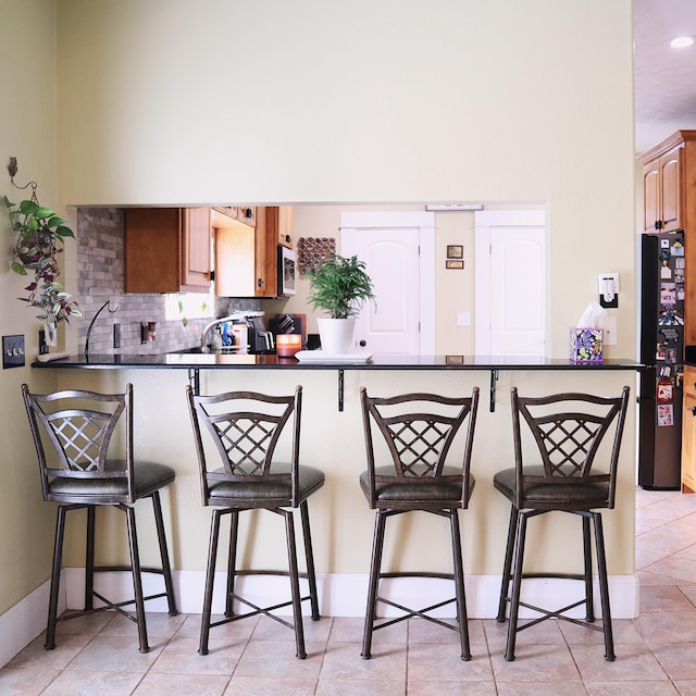 kitchen featuring a kitchen bar, kitchen peninsula, and black fridge