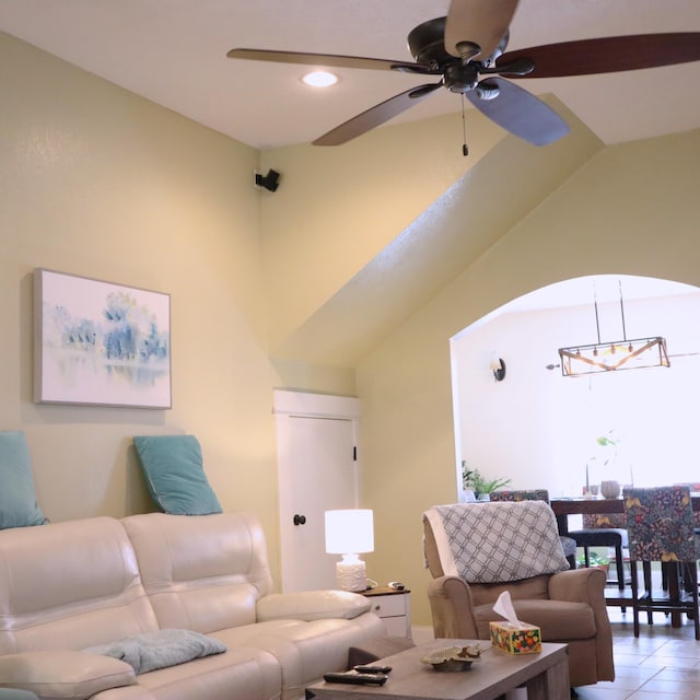 living room featuring tile patterned flooring, ceiling fan with notable chandelier, and vaulted ceiling